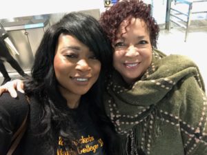 Two women smiling together indoors.